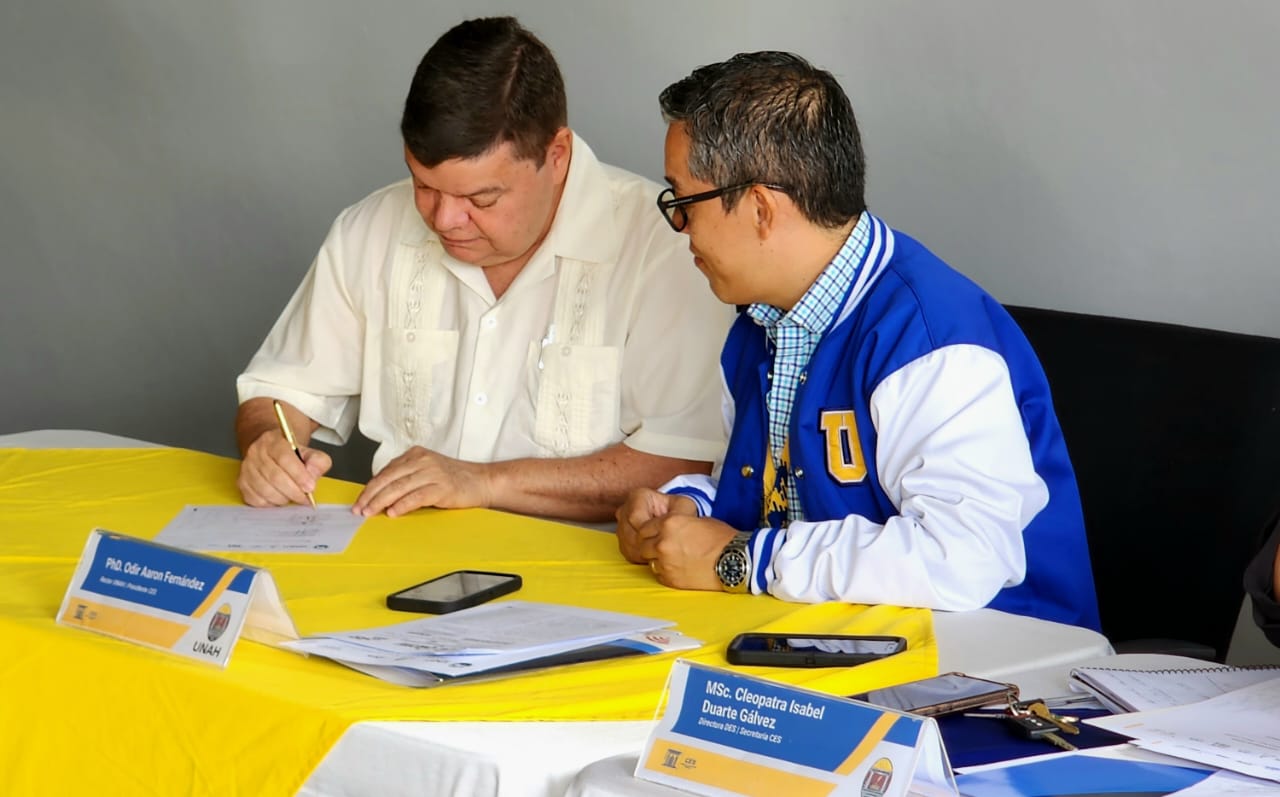 Dos personas firmando representando la integración de USAP en la Red de Internacionalización de la Educación Superior de Honduras (RediEShn.)