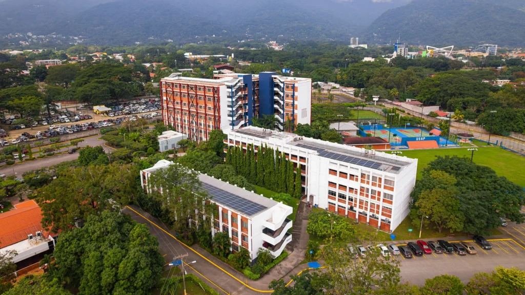 Vista aérea del campus de USAP con edificios académicos, áreas verdes, canchas deportivas y montañas al fondo.