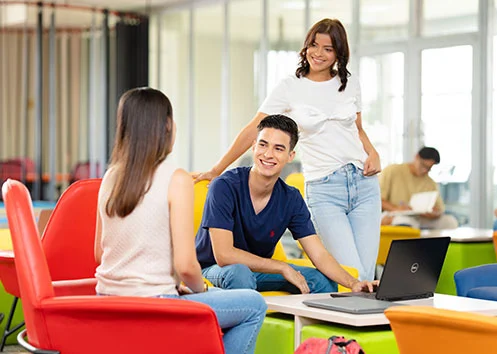 Tres estudiantes universitarios reunidos trabajando en equipo en el espacio coworking de la Universidad de San Pedro Sula (USAP).